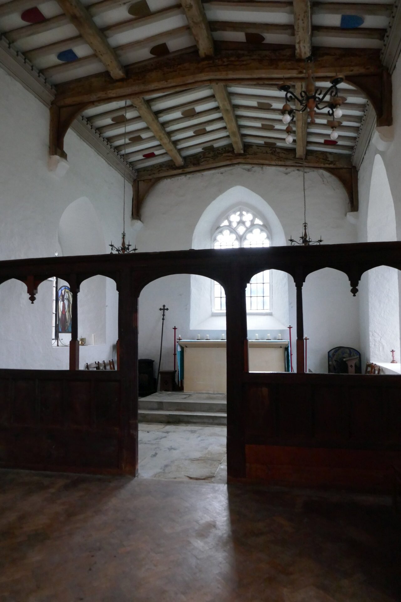 The interior, plain whitewashed walls, and the oak screen separating the nave and chancel areas