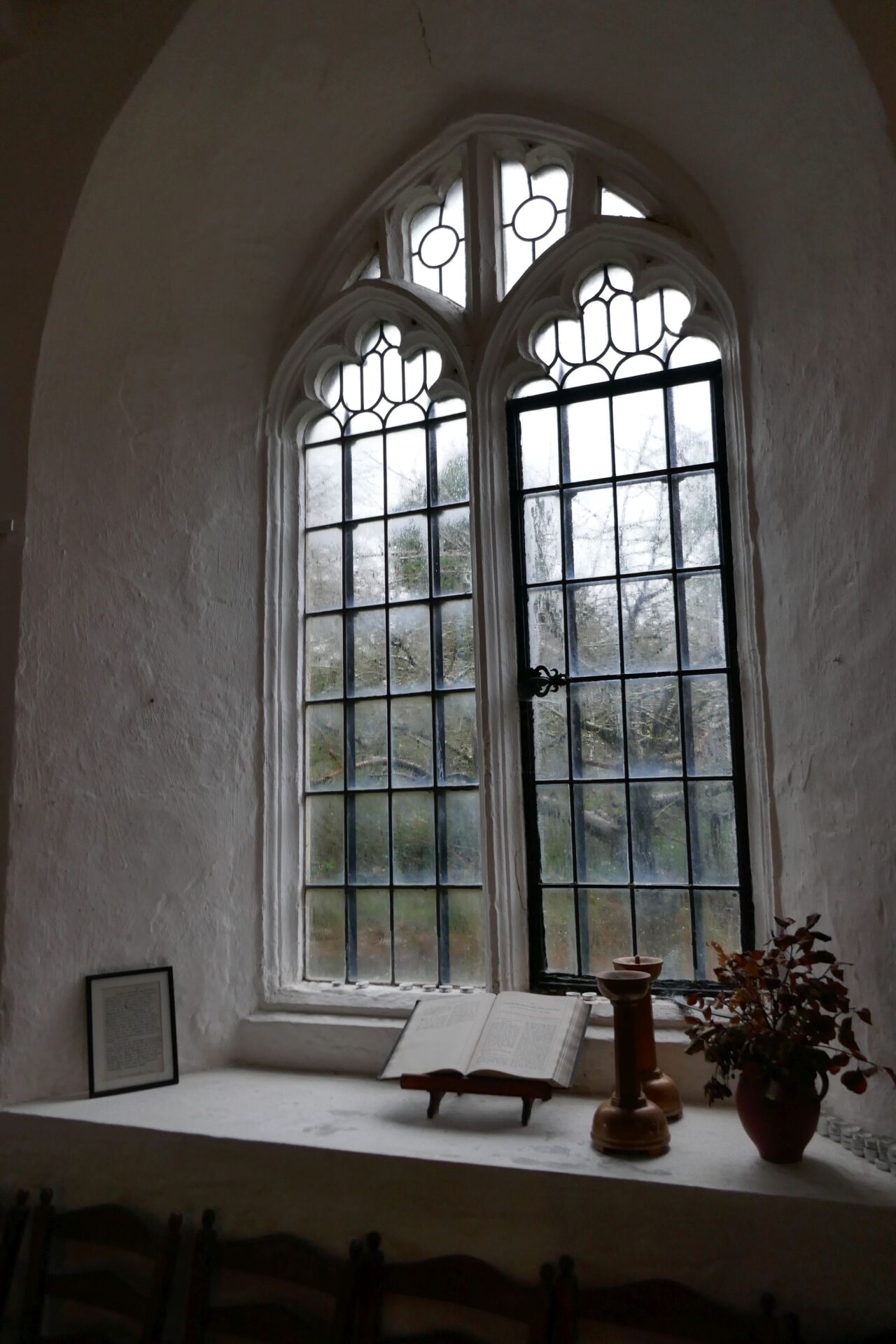 a window on the south wall, with bible, candlesticks, and flower arrangement